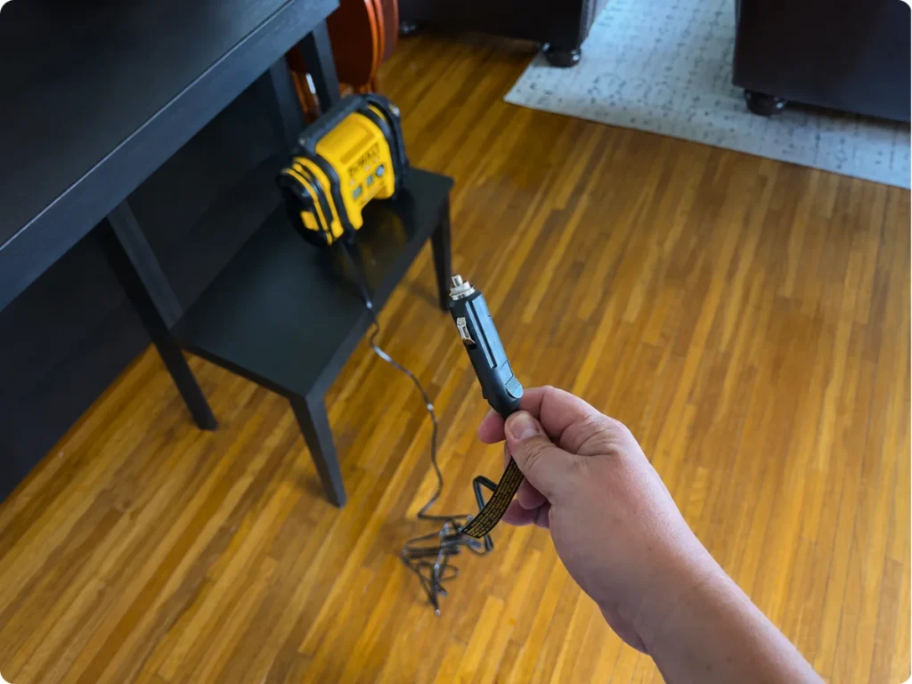 DEWALT DCC020IB 12V vehicle power plug held beside the inflator